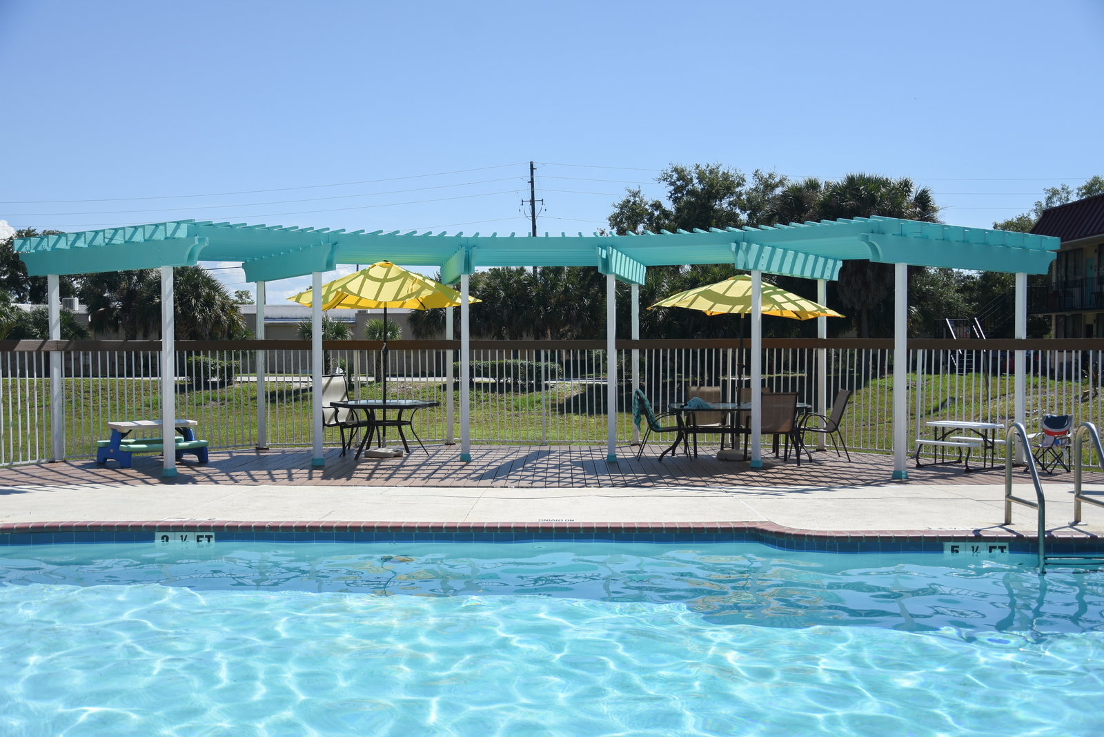 Resort-style pool with a shaded pergola and umbrellas